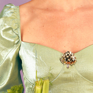 bijou à clip en forme d'artichaut sur décolleté robe velours verte