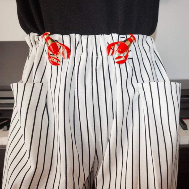 Bijou clip en forme de homard rouge porté à la paire sur ceinture pantalon rayé