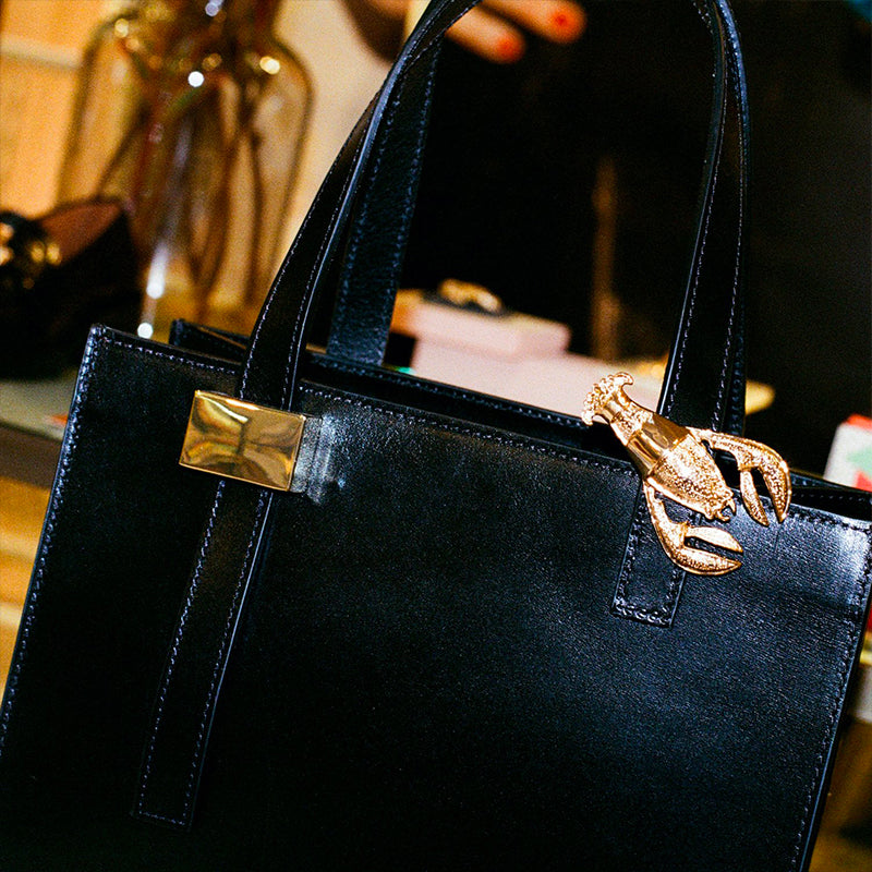 Bijou clip en forme de homard doré sur sac noir