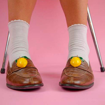 Bijou clip en forme de citron jaune porté sur mocassins et chaussettes blanches