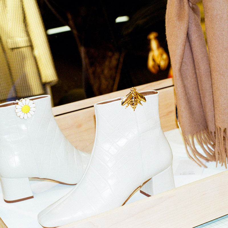 Bijou clip en forme d'abeille dorée porté sur bottine blanche