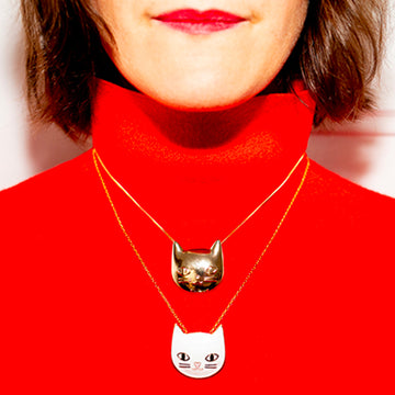 Bijou clip en forme de chat doré porté sur collier et pull rouge