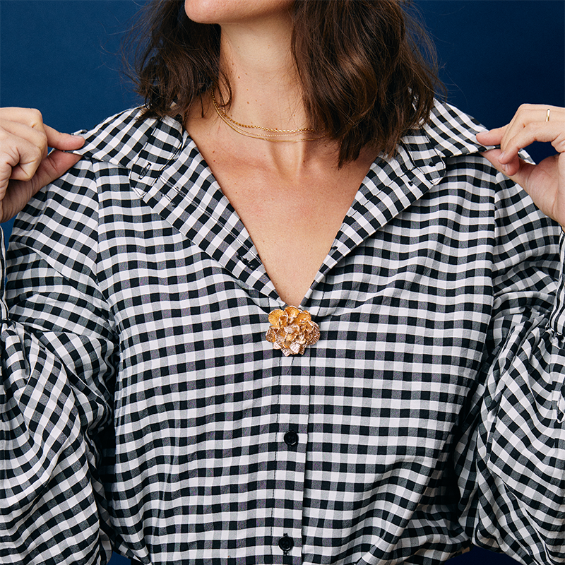 Bijou clip rose des sables porté sur une chemise à carreaux de couleur noir et blanc