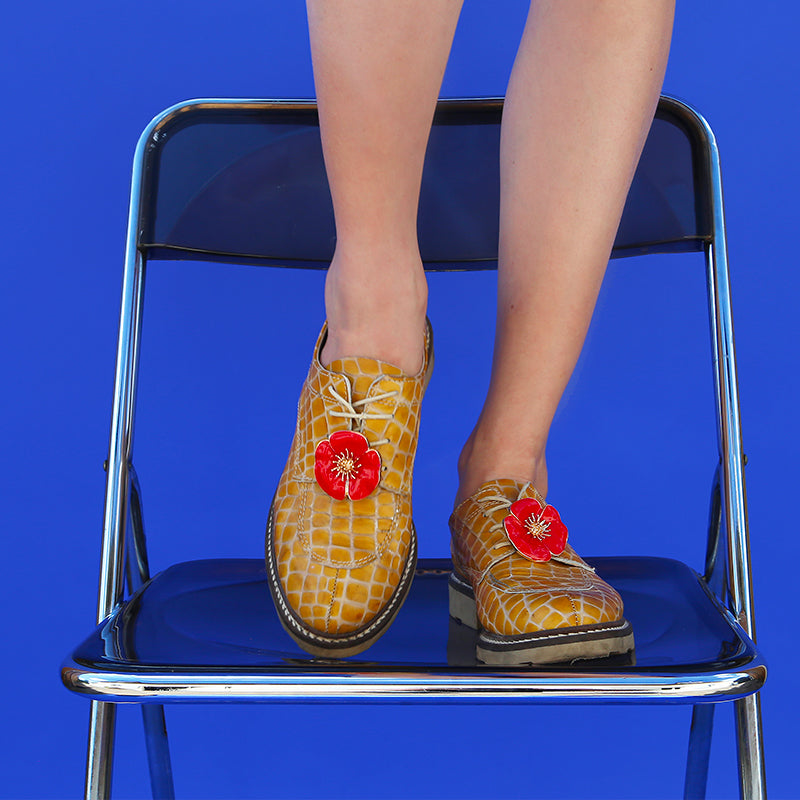 Bijou clip en forme de coquelicot rouge porté sur chaussures derbies