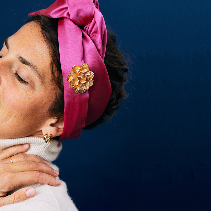 Bijou clap paris, modèle rose des sables doré sur turban en soie rose porté par une femme. collection pour octobre rose
